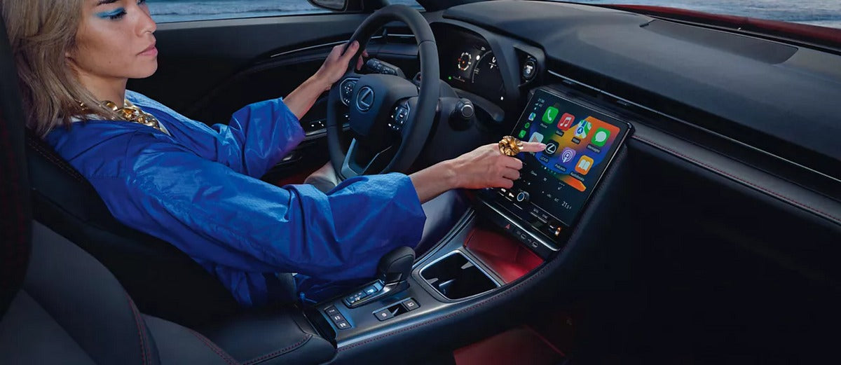 Driver using Apple CarPlay on a car dashboard screen with navigation and apps visible, symbolizing connected car technology and its impact on insurance coverage.