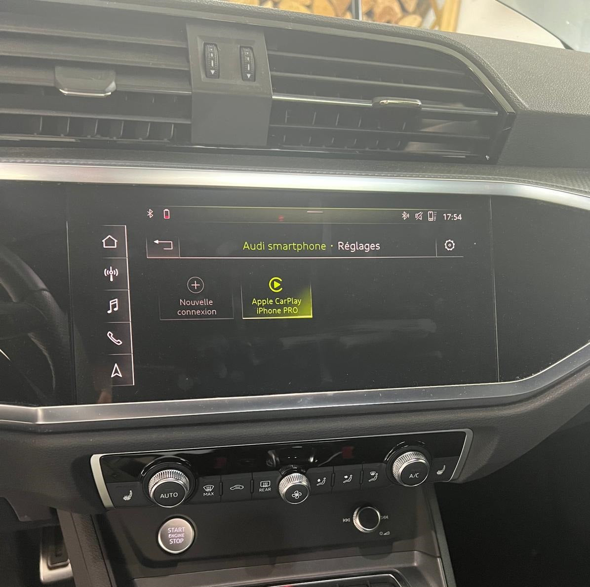 Car dashboard with infotainment system displaying Audi smartphone settings.