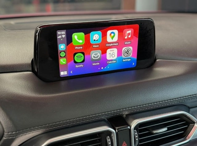 Apple CarPlay interface integrated into a Mazda vehicle, displaying navigation, communication, and media apps on the touchscreen.